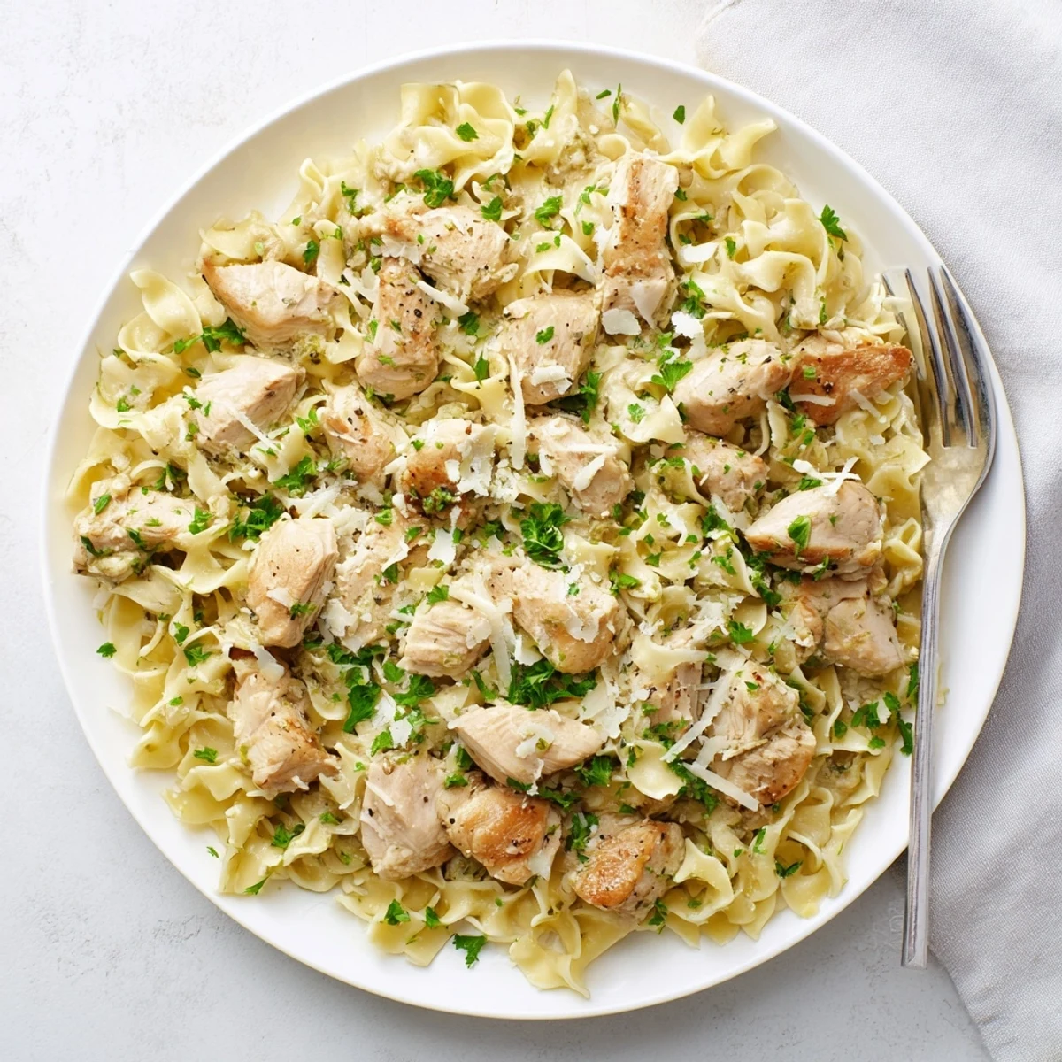 Savory sliced chicken atop glossy egg noodles finished with melted butter and chopped herbs in a family-friendly dinner