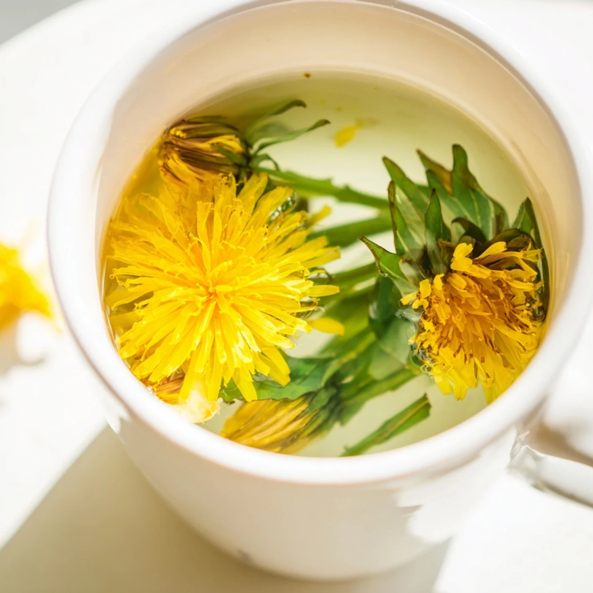Golden dandelion tea steaming in a white ceramic cup with fresh yellow flowers