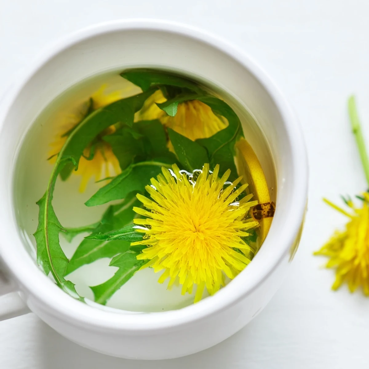 Clear glass mug of earthy dandelion tea garnished with vibrant fresh petals