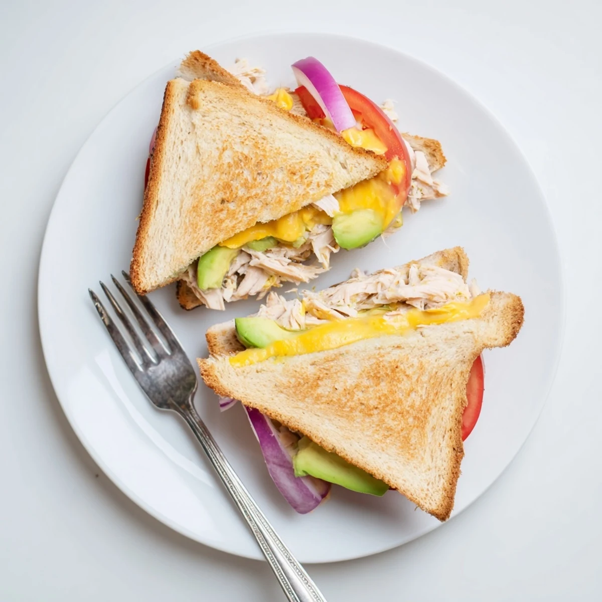 Sliced chicken avocado melt sandwich cross-section showing creamy avocado layers and melted cheddar on buttery toasted bread