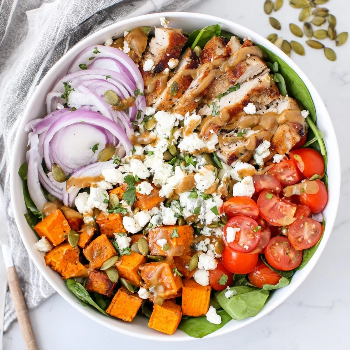 Golden maple Dijon chicken glazed and sliced over roasted sweet potato cubes in a bowl