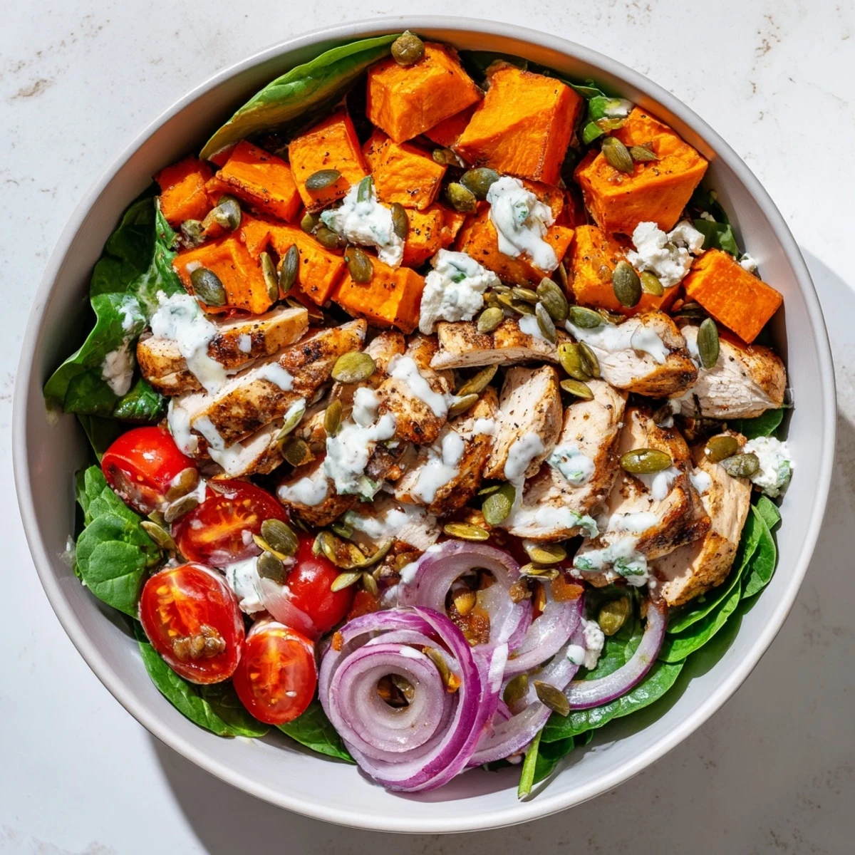 Sliced maple Dijon glazed chicken breast served atop roasted sweet potatoes in a wholesome grain-free bowl