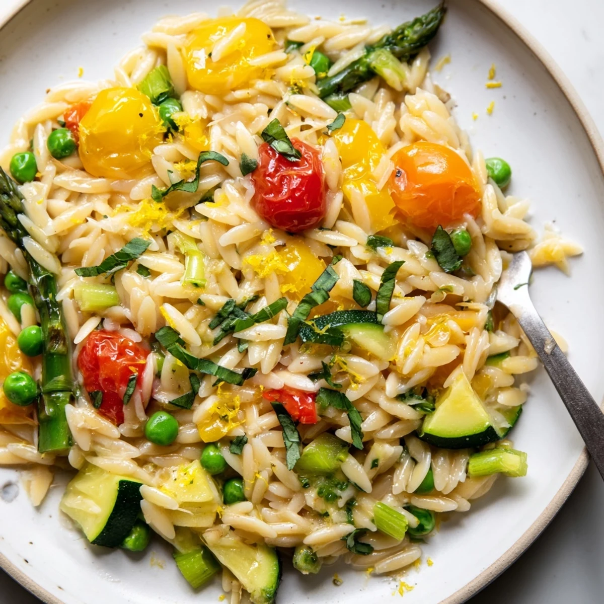 Creamy Orzo Primavera tossed with bright vegetables and fresh herbs in skillet