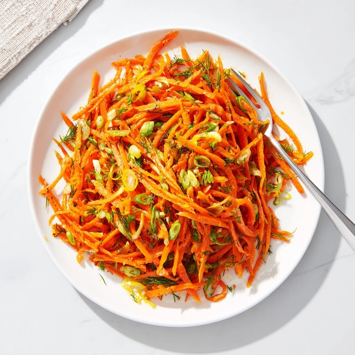 Marinated Lemon Dill Carrot Salad in a white bowl with fresh herb garnish