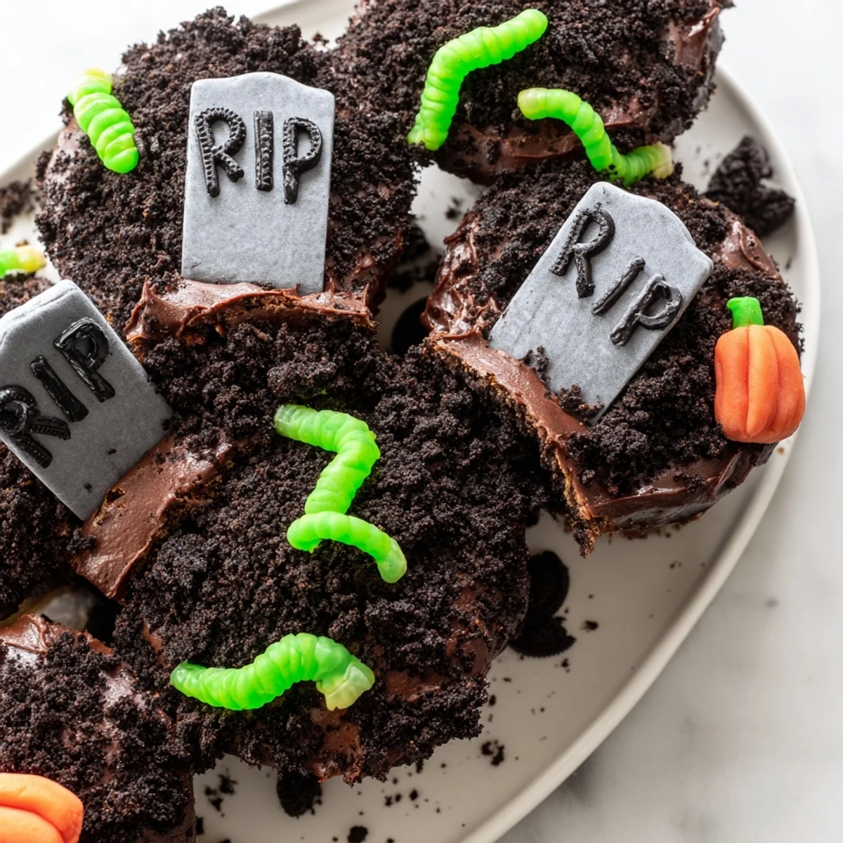 Frosted Pull Apart Graveyard Cupcakes decorated with cookie tombstones and candy pumpkins on a tray