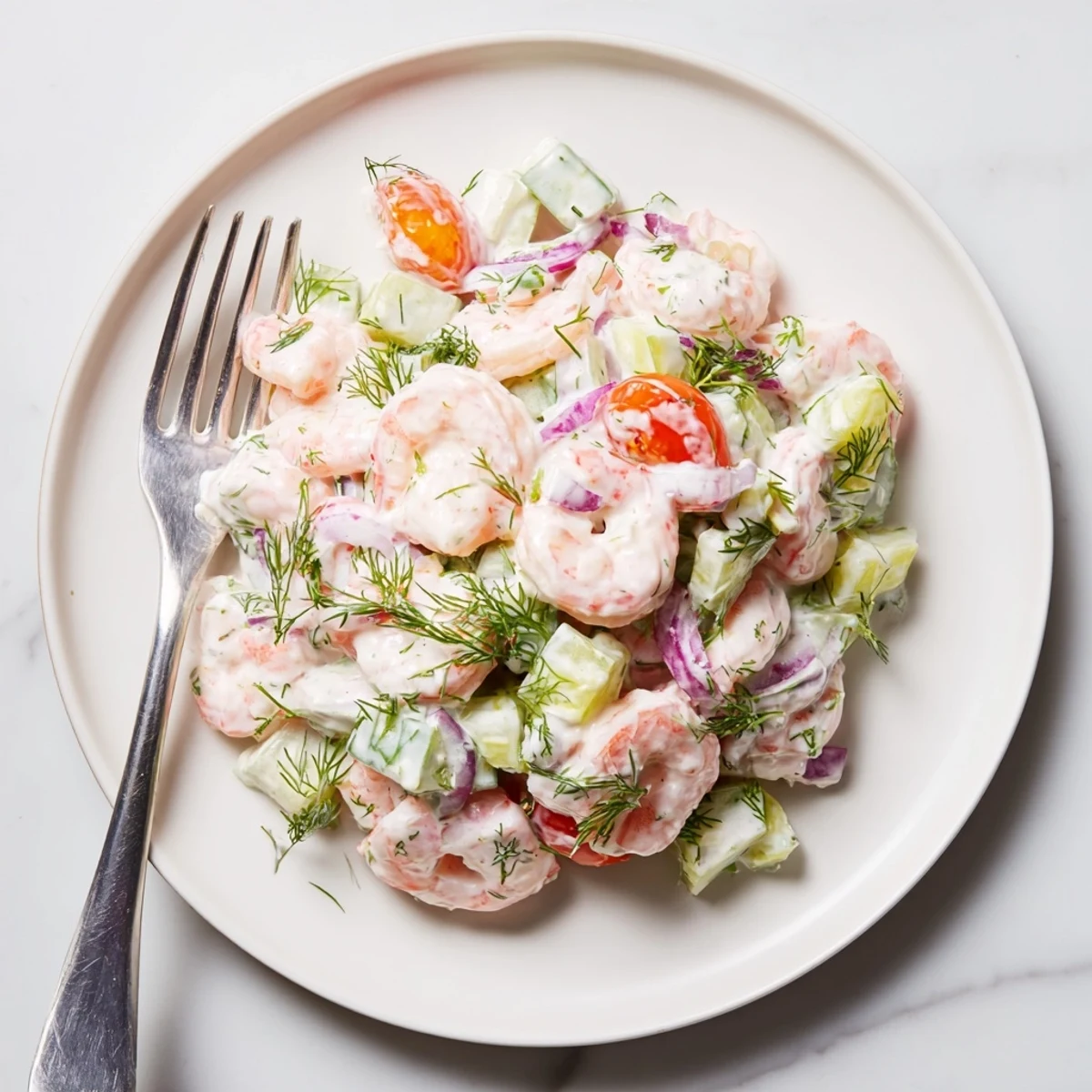 Shrimp salad recipe served over greens with cherry tomatoes and fresh dill
