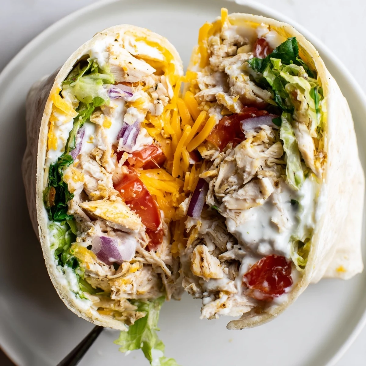 Warm Cheesy Garlic Chicken Wraps sliced in half, oozing melted cheese