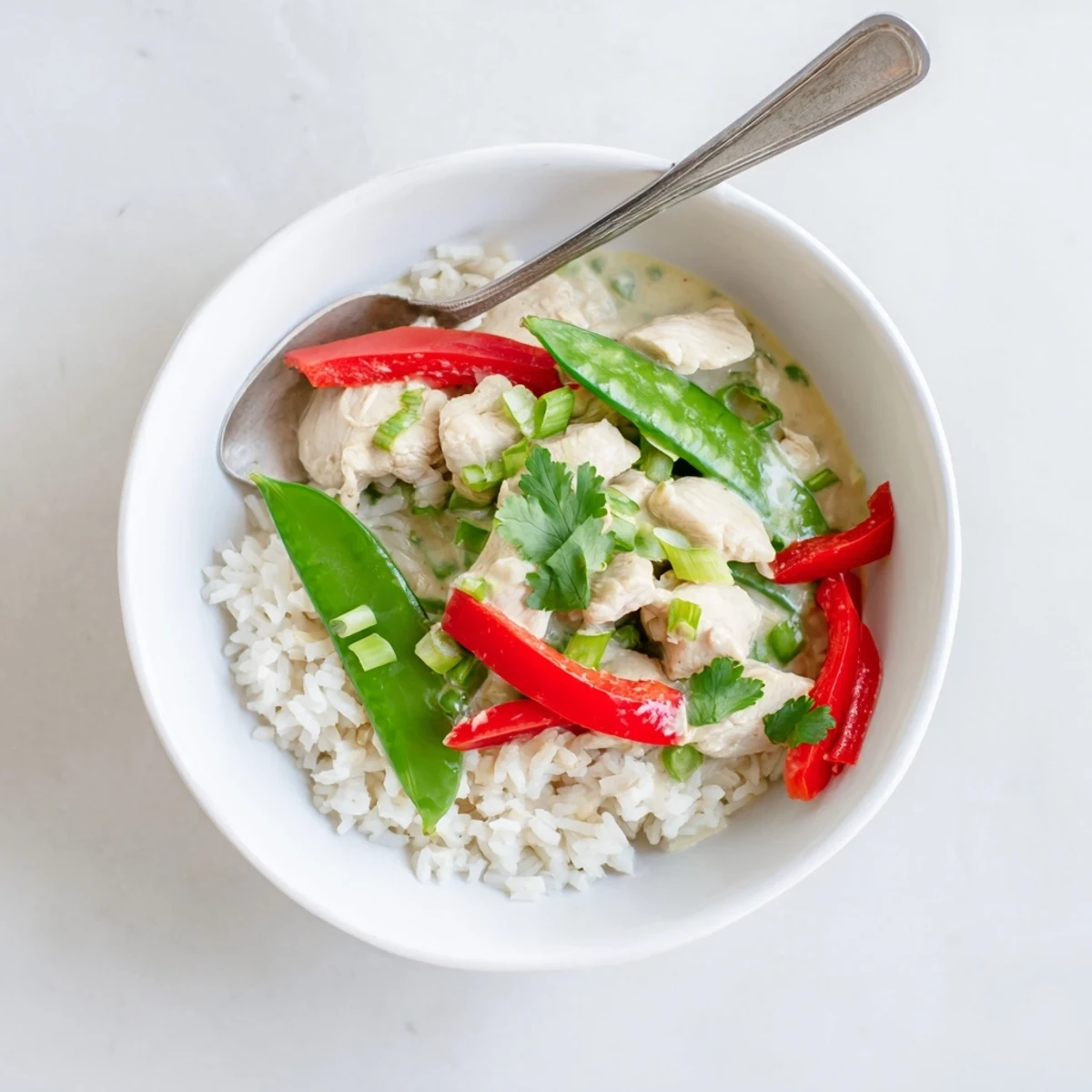 Creamy coconut chicken rice bowl topped with colorful bell peppers and fresh cilantro garnish