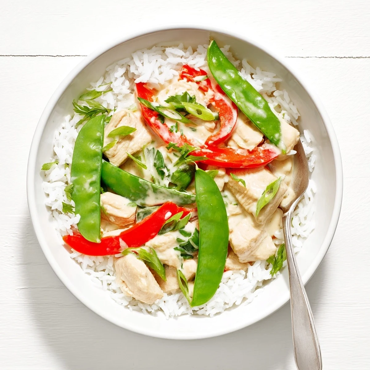 Savory coconut chicken served over fluffy jasmine rice with snap peas and toasted coconut flakes