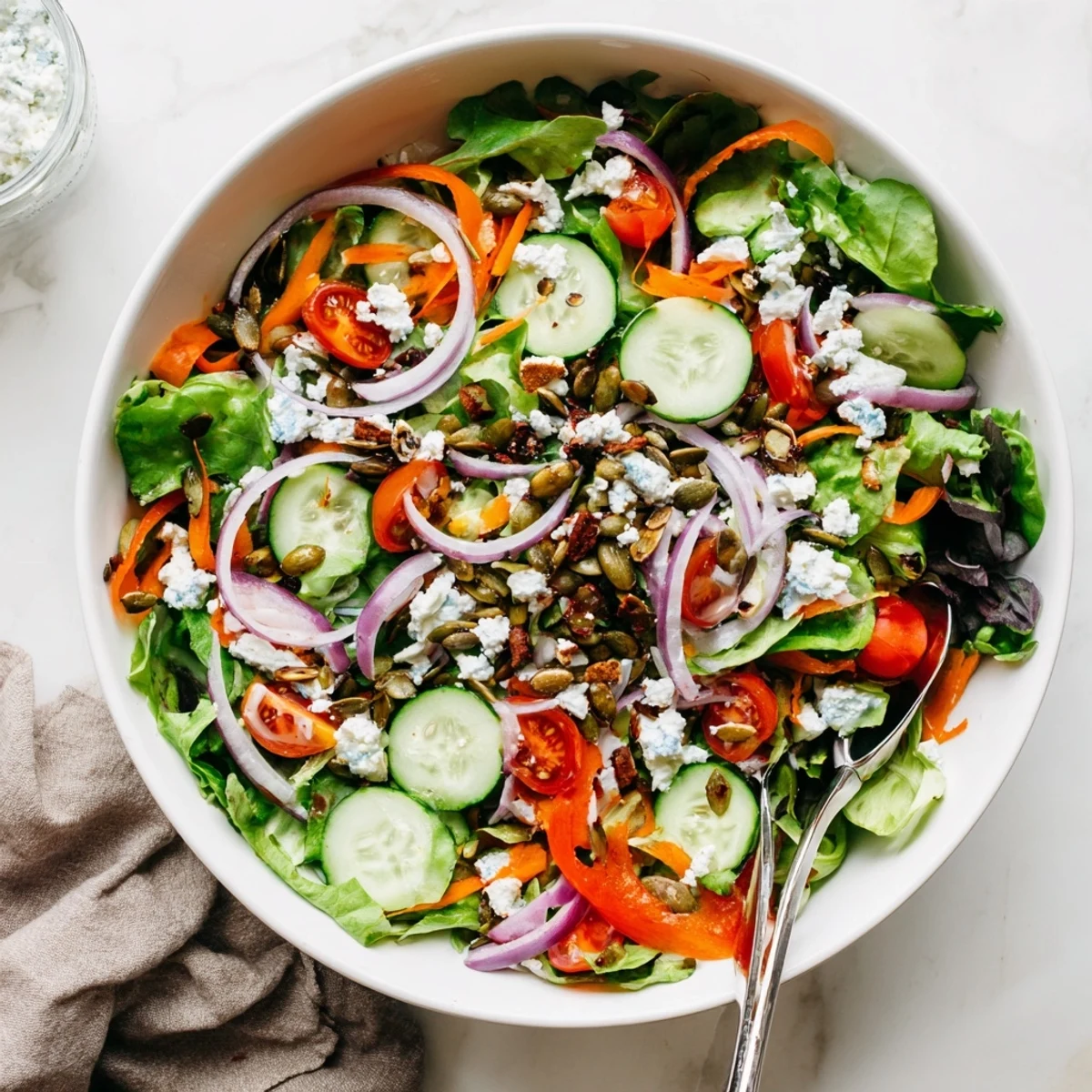 Fresh garden salad featuring crisp seasonal vegetables, shredded carrots, and bell pepper slices tossed in tangy olive oil vinaigrette