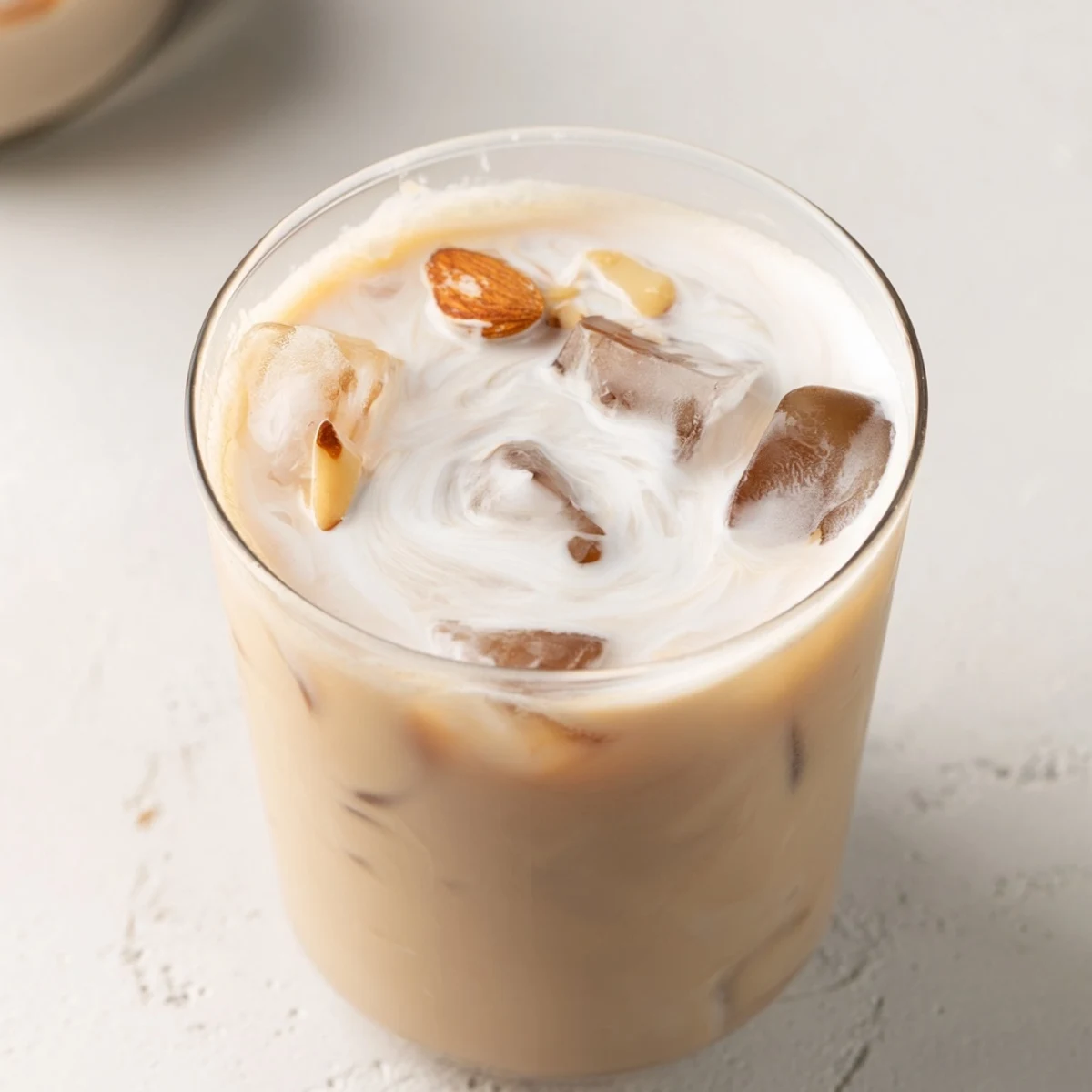 Light nutty almond milk drink with creamy swirl topped with cinnamon in a chilled serving glass