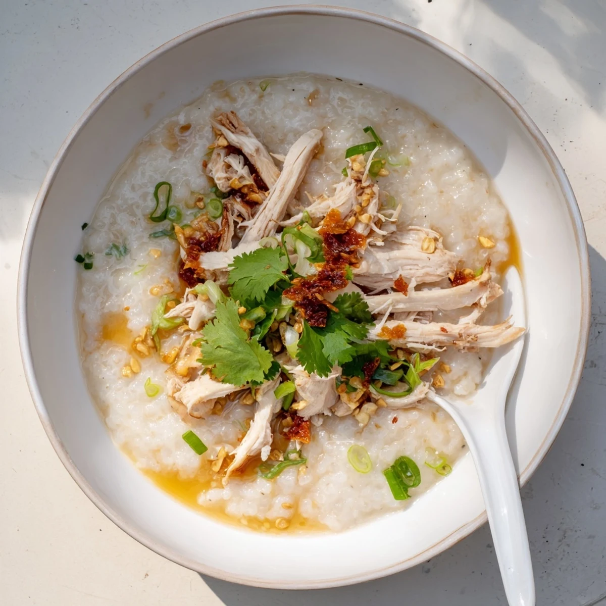 Creamy chicken congee topped with fresh scallions and drizzled with aromatic sesame oil