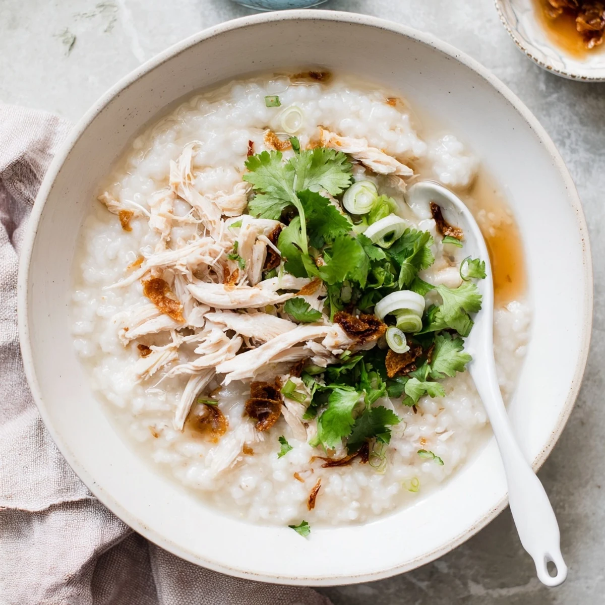Steaming bowl of Chinese chicken congee garnished with cilantro and crispy fried shallots