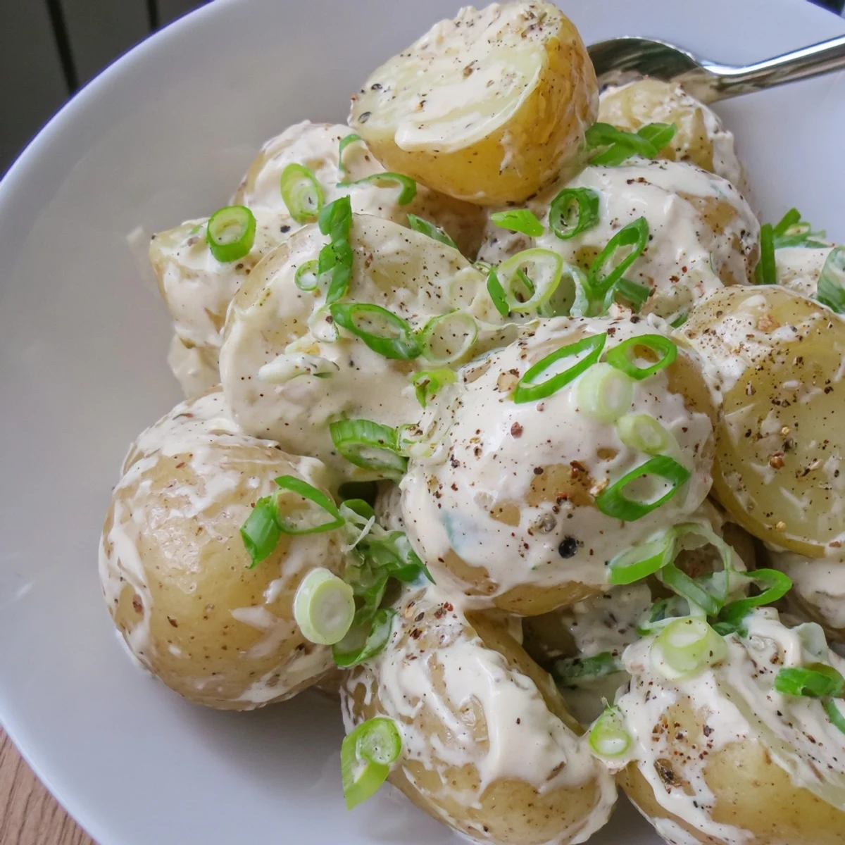 Creamy Sour Cream And Onion Potato Salad tossed with scallions, chilled for barbecue