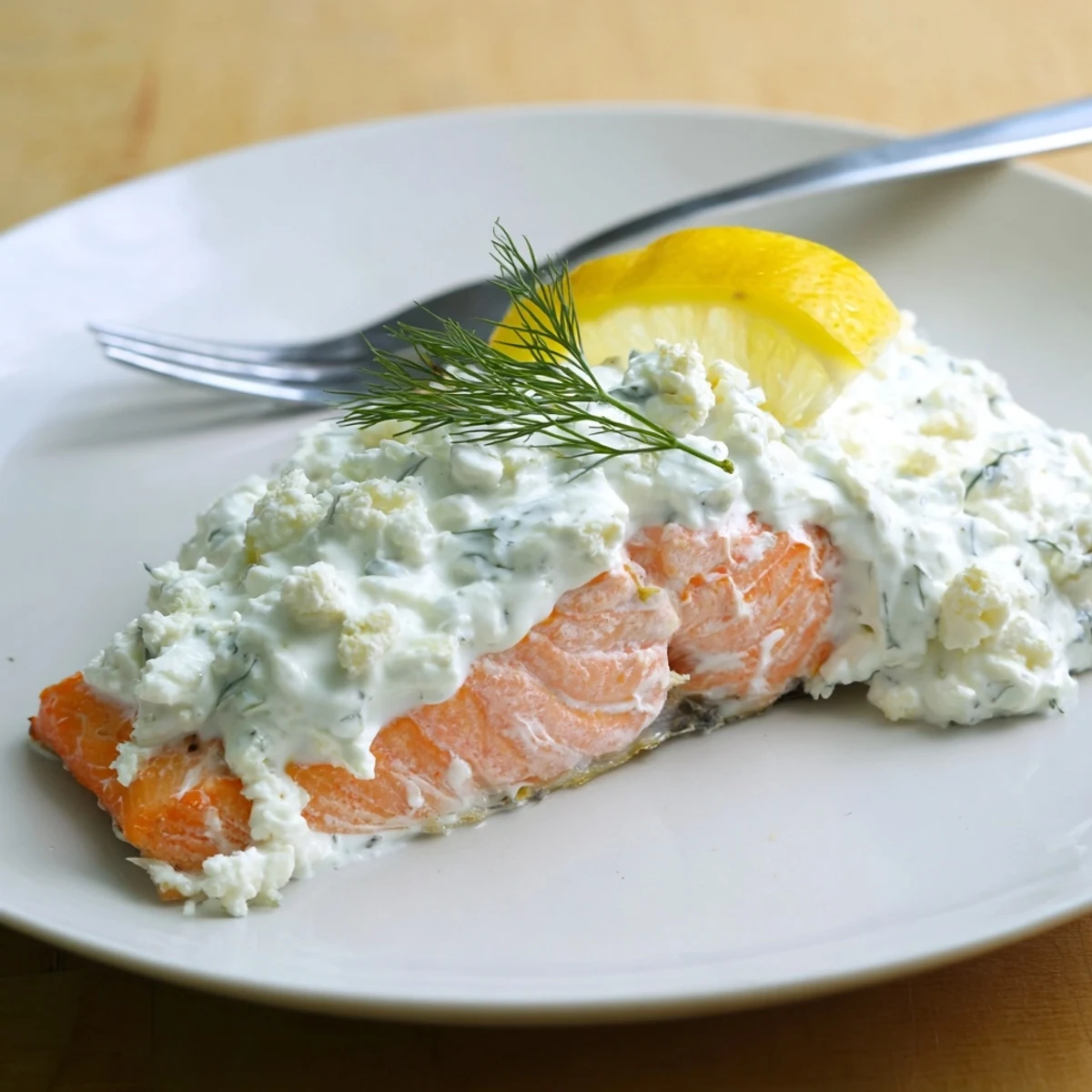 Pan roasted Salmon With Feta Dill Sauce garnished with lemon wedges and fresh dill