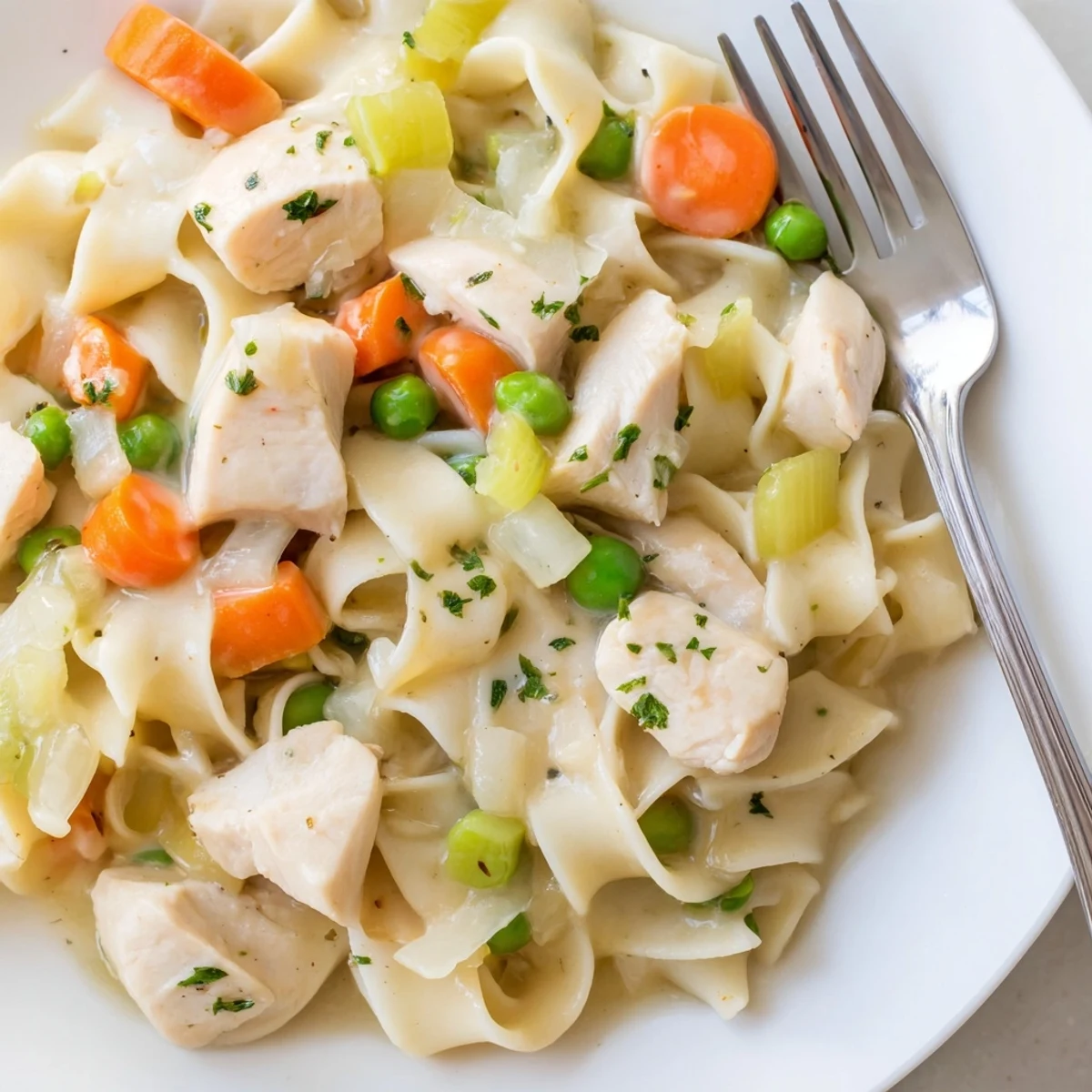 Creamy one pot chicken and noodles served in a white bowl garnished with fresh parsley