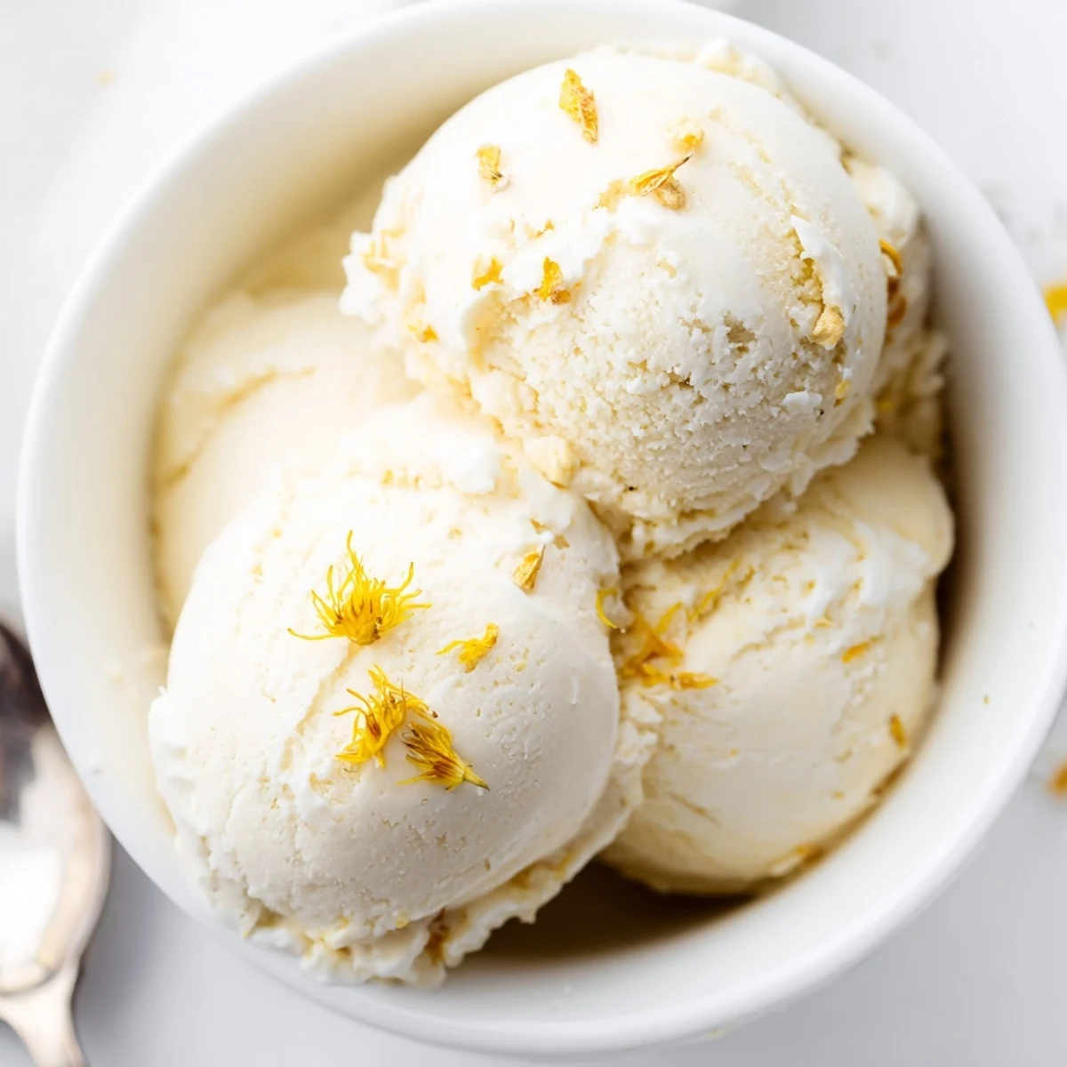 Creamy dandelion honey ice cream scooped into a vintage bowl with golden floral swirls visible