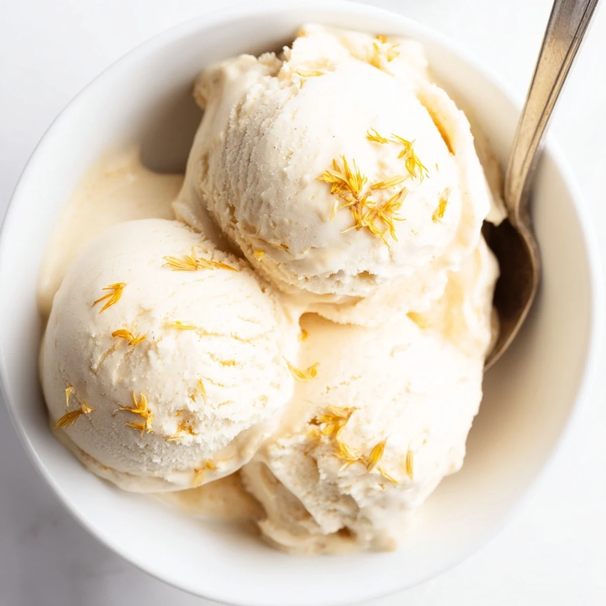 Golden scoops of dandelion honey ice cream melting slightly on a rustic wooden serving board