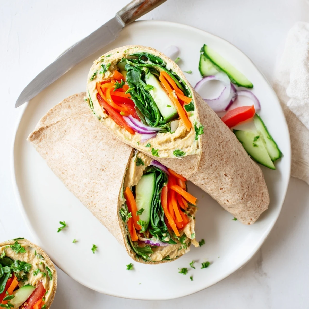 Mediterranean-style hummus wrap sliced diagonally revealing layers of colorful vegetables tender greens and creamy spread