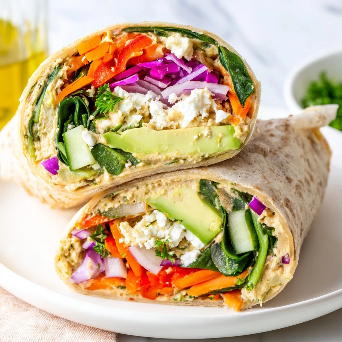 Mediterranean hummus veggie wrap recipe sliced diagonally revealing colorful layers of fresh vegetables