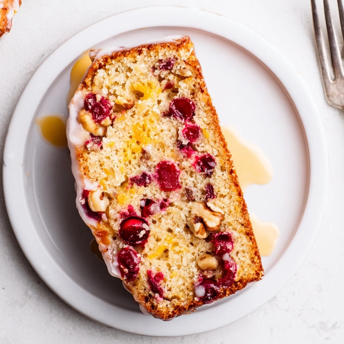 Sliced Cranberry Orange Bread with glossy citrus glaze, steaming on wire rack.