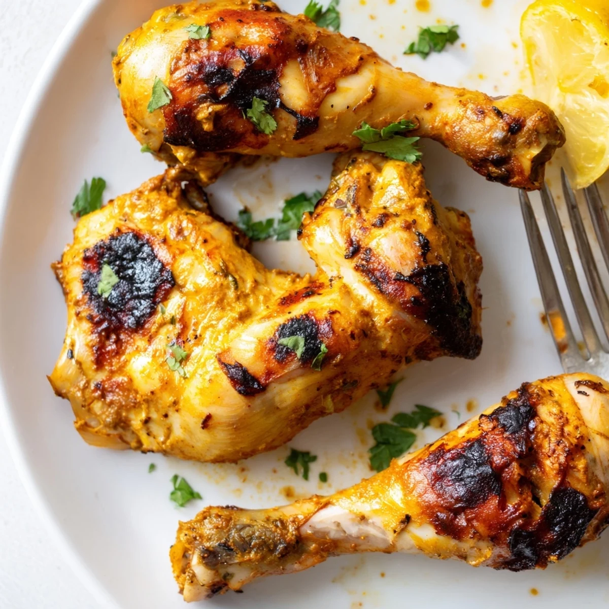 Tandoori Chicken sizzling with charred edges, garnished with cilantro and lemon