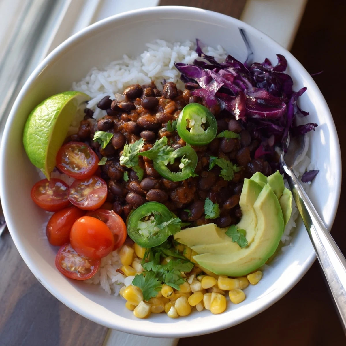 Hearty black bean and rice bowl topped with sliced avocado and fresh cilantro