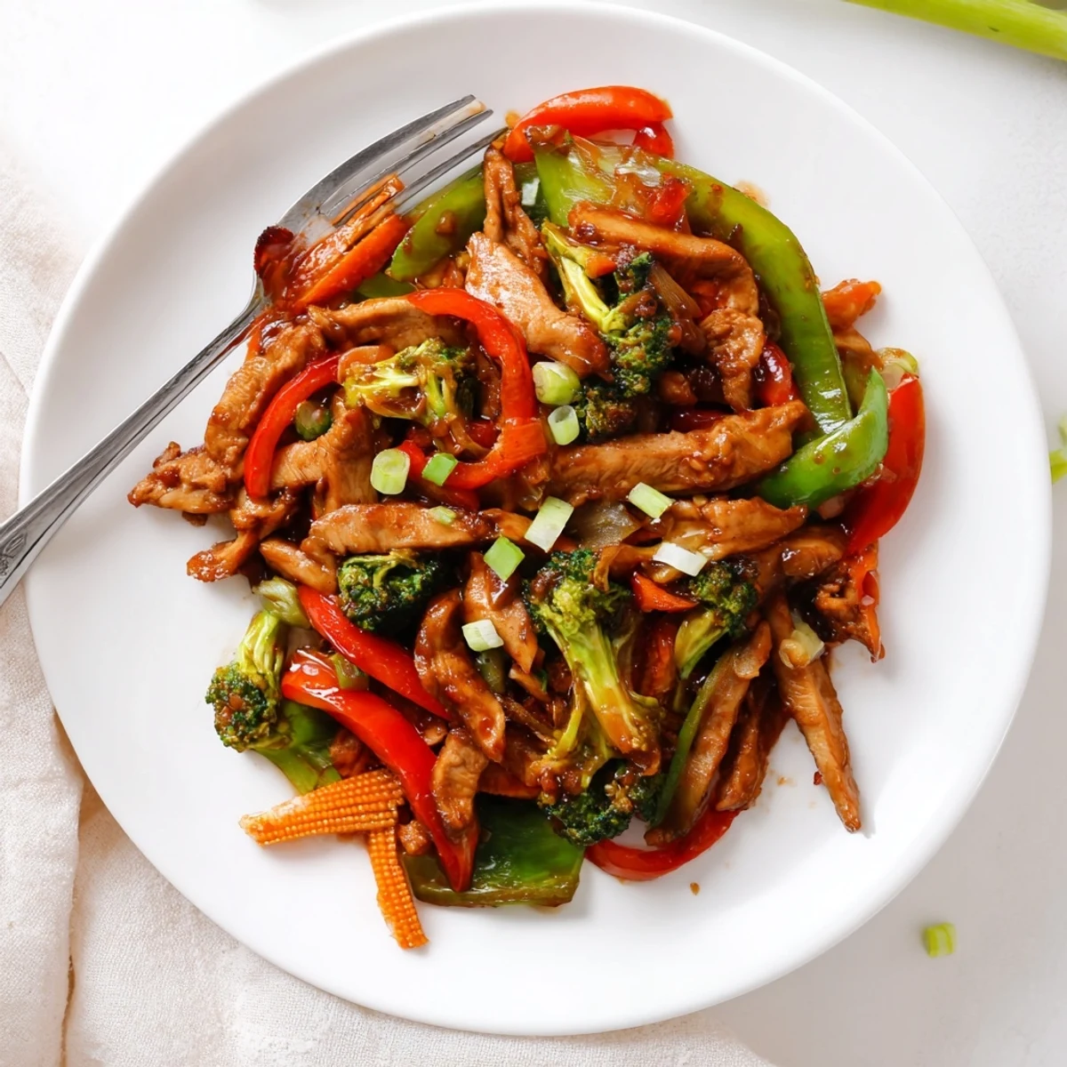 Hunan chicken glistening with spicy sauce over crisp broccoli and colorful bell peppers
