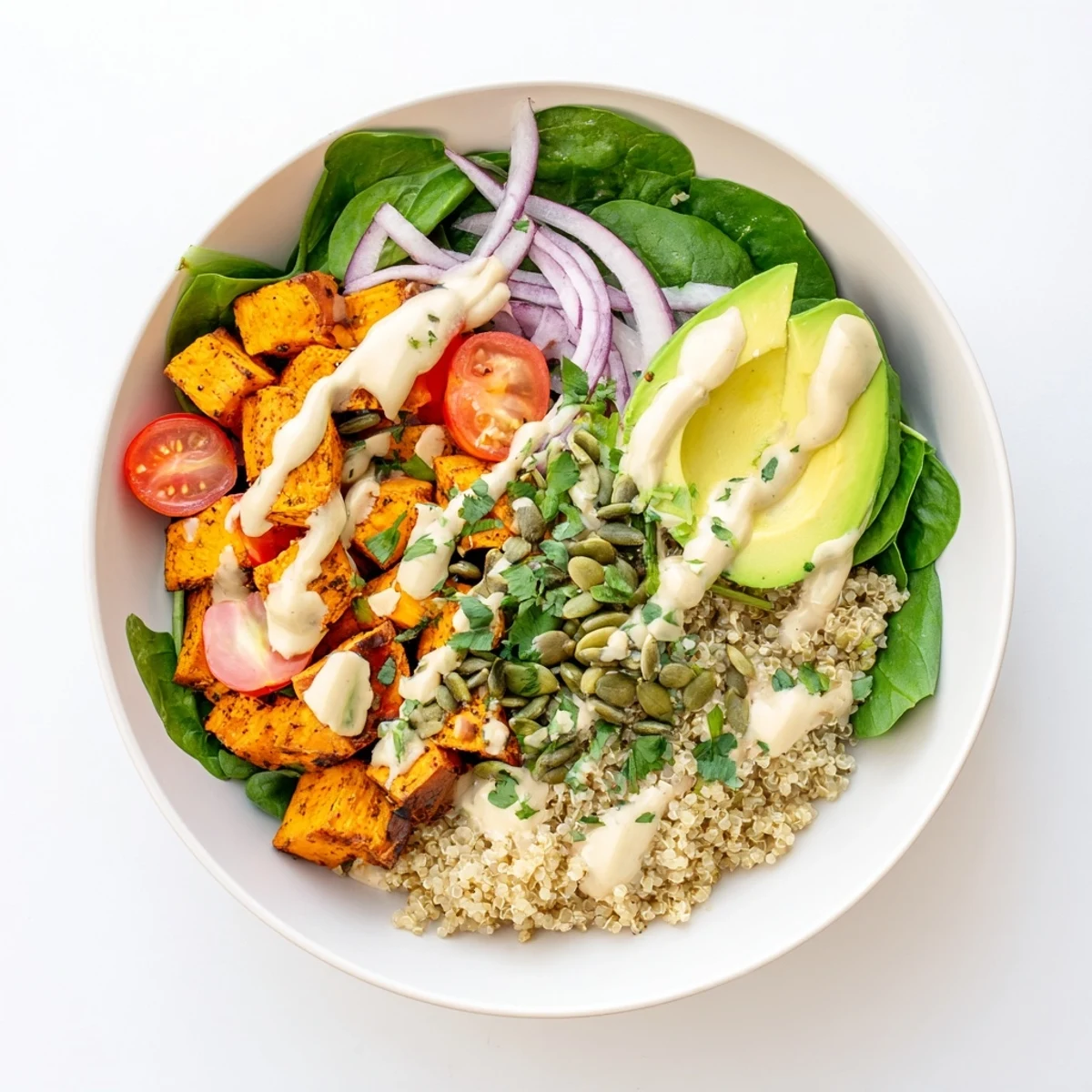 Colorful sweet potato bowl served over fluffy quinoa with cherry tomatoes and fresh baby spinach