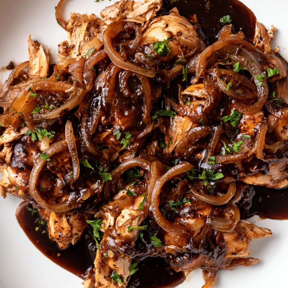 Slow cooker balsamic chicken garnished with fresh parsley alongside fluffy mashed potatoes