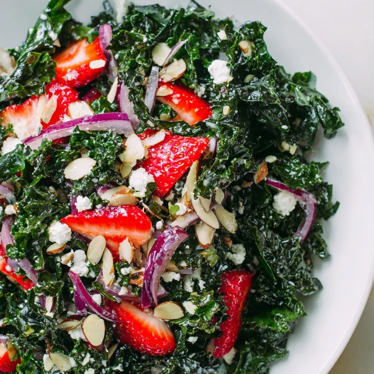 Fresh strawberry kale salad tossed in sweet honey lemon dressing with toasted almonds