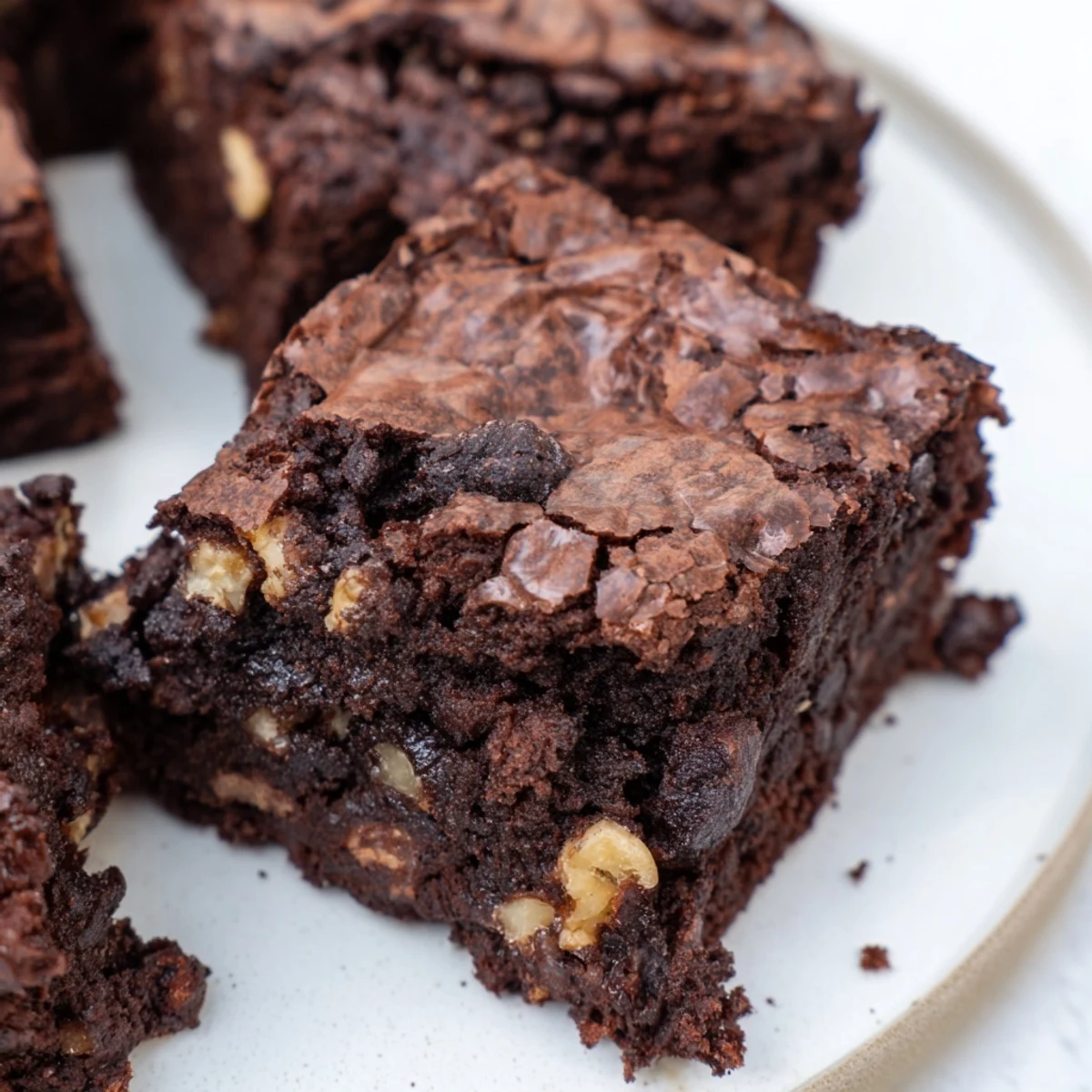 Gooey homemade brownies with a shiny crust, dusted with cocoa powder and ready to share