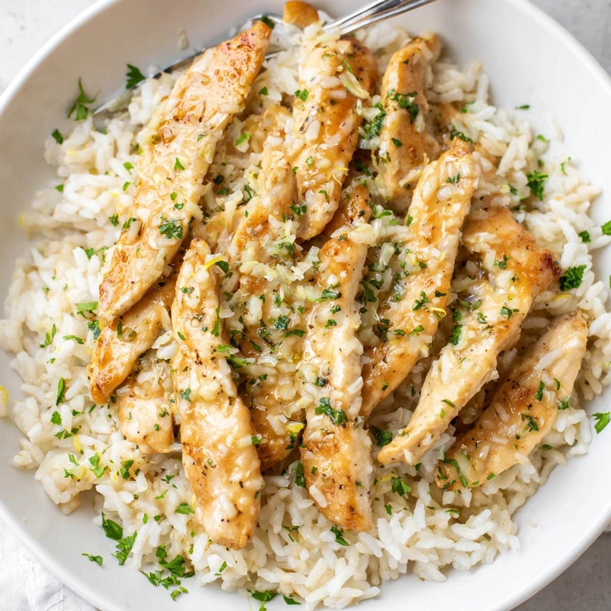 Tender seared chicken scampi piled over creamy garlic parmesan rice with fresh parsley