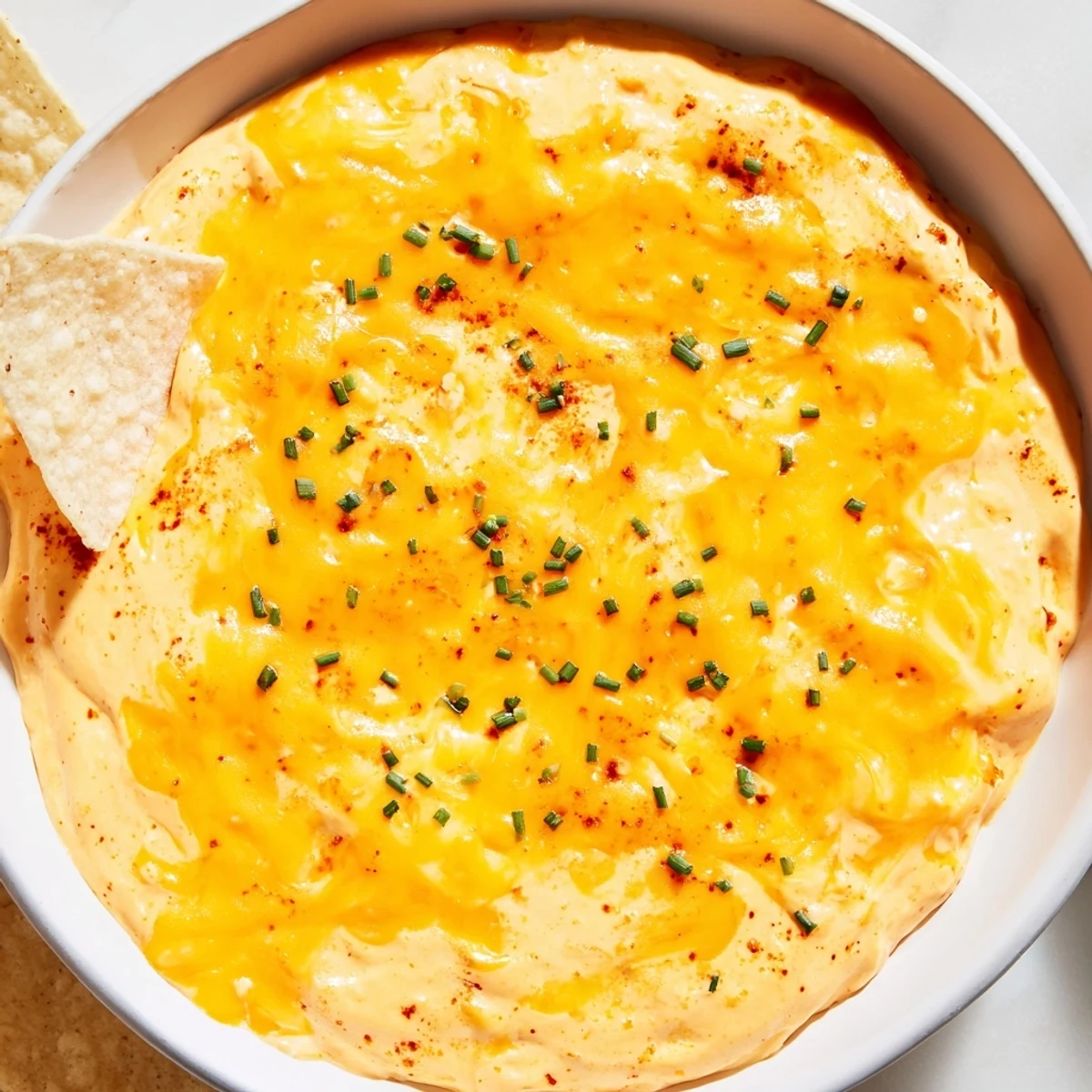 Creamy cheese dip in a warm bowl surrounded by golden tortilla chips