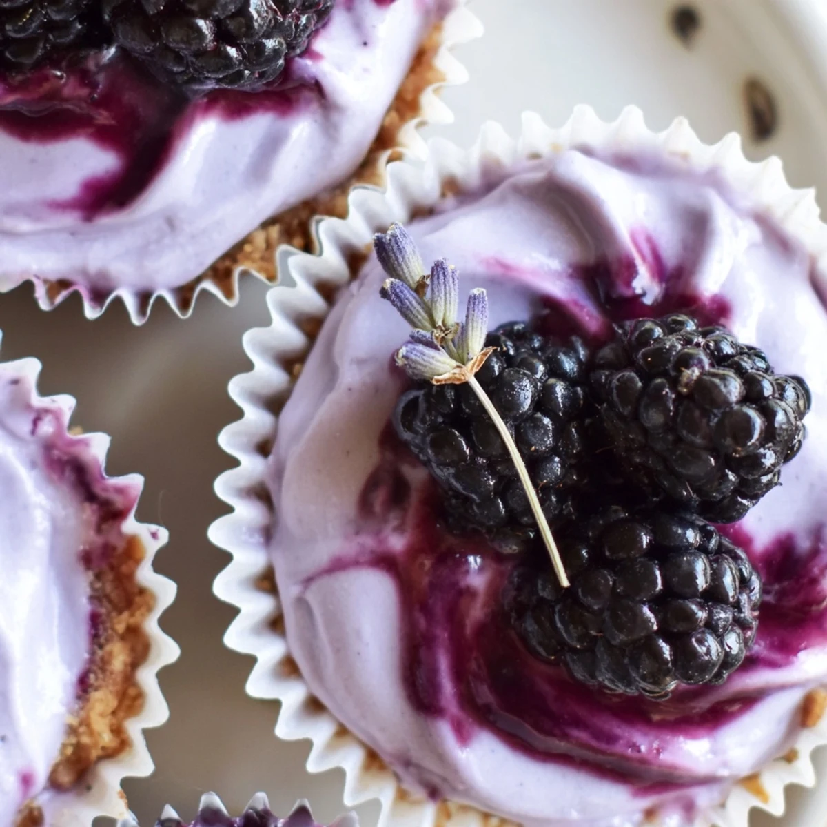 Creamy mini blackberry lavender cheesecakes topped with glossy purple berry compote in muffin liners