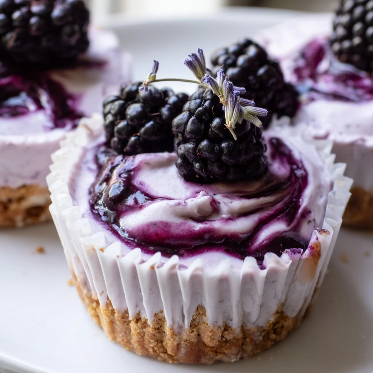 Individual no bake blackberry lavender cheesecakes with buttery graham crust and fresh berry drizzle