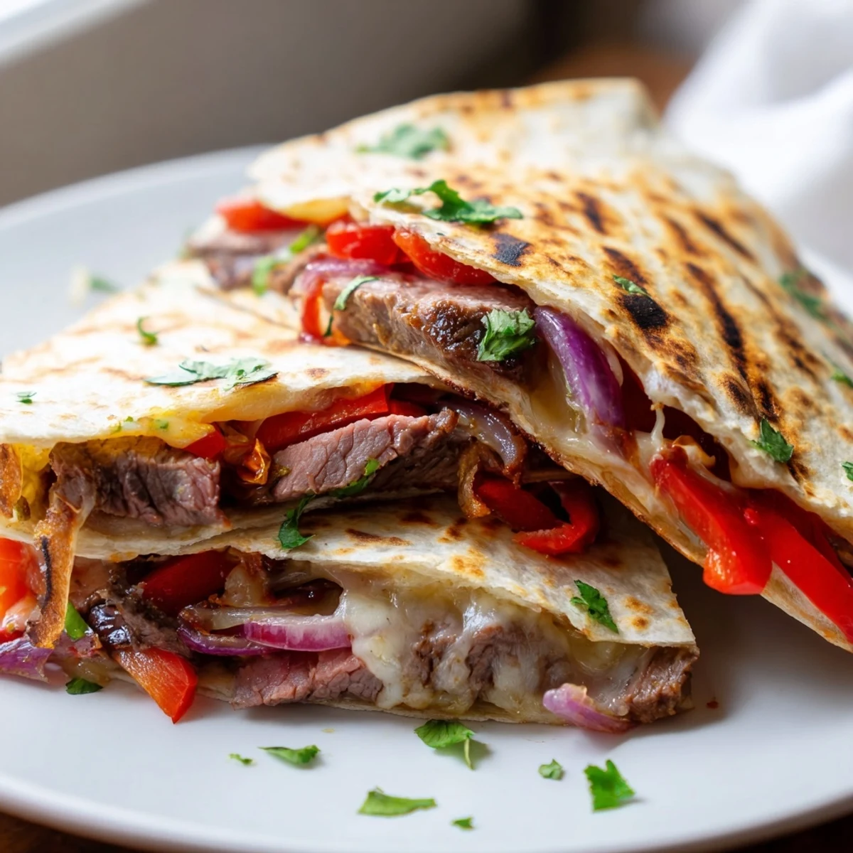 Steak quesadillas cut into triangles, revealing tender beef and melted cheddar filling