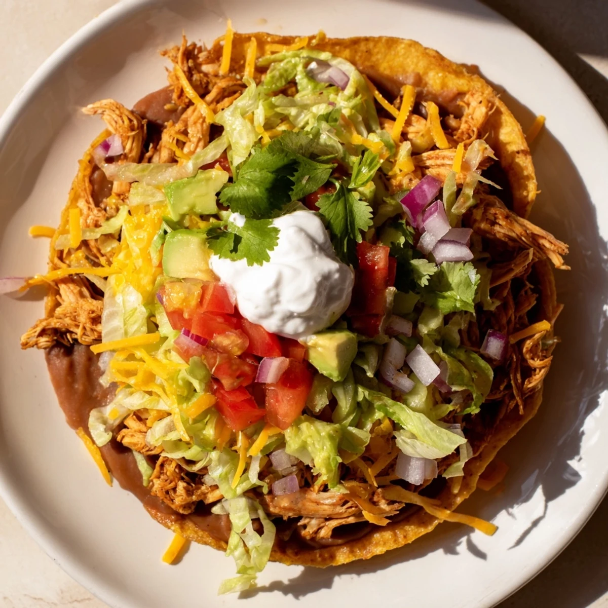 Crispy Chicken Tostadas topped with juicy chicken, fresh veggies, and creamy cheese.  