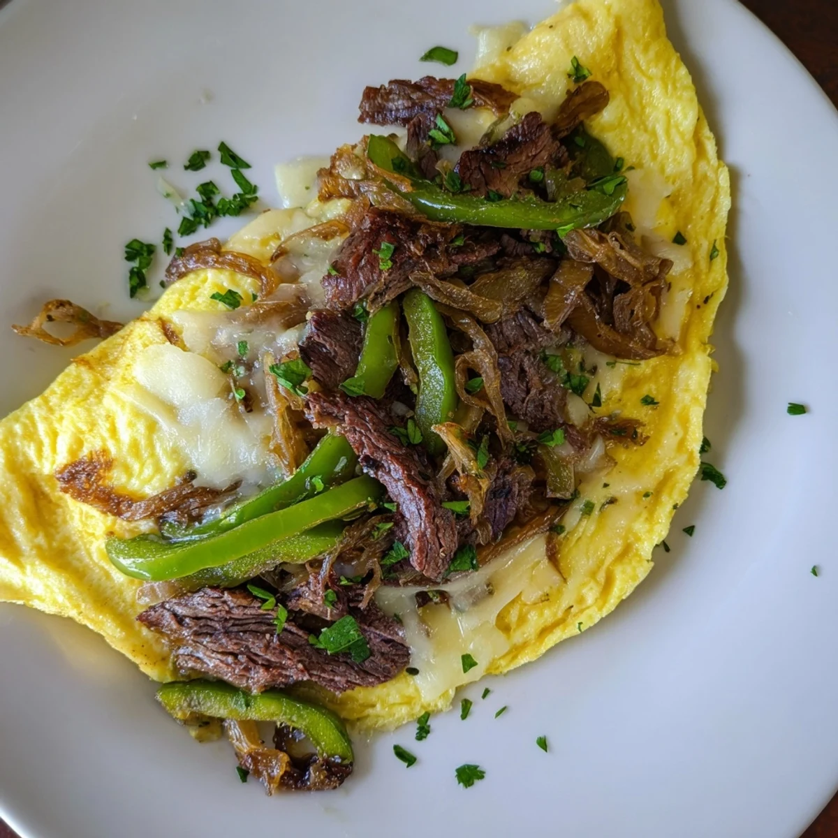 Golden Philly cheesesteak omelette stuffed with tender steak, peppers, and melted provolone.  