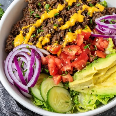 Colorful burger bowls featuring crisp lettuce, ripe avocado, and tangy pickles
